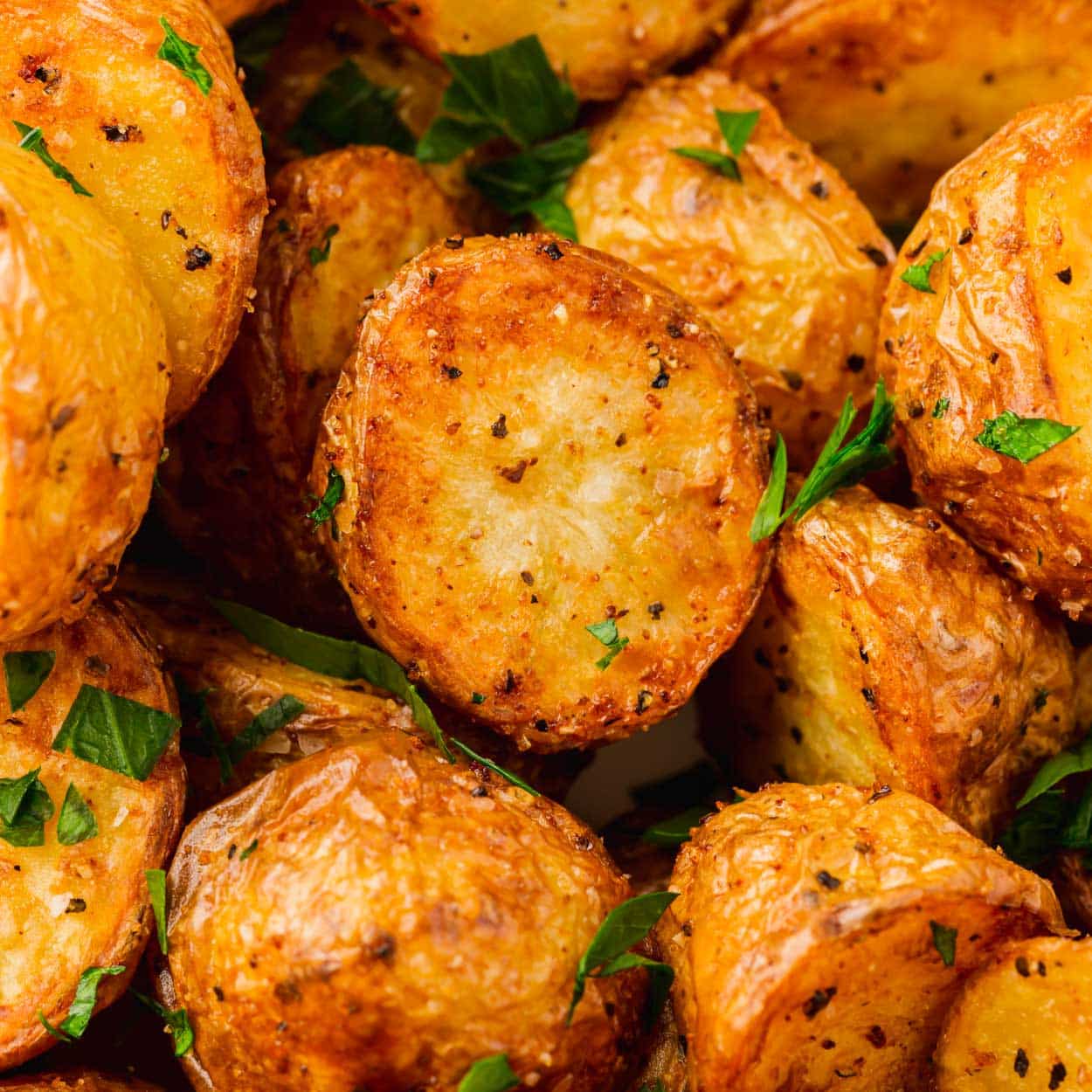 closeup view of roasted potatoes garnished with fresh herbs.