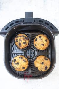 vertical photo showing air fryer blueberry muffins in air fryer basket, cooked