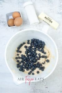vertical photo showing blueberries added to the batter mixture