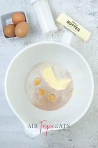 vertical photo showing butter, milk, eggs and vanilla in a bowl
