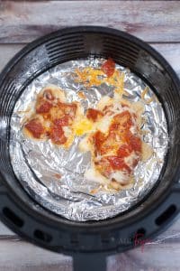 vertical photo showing cooked pizzas in air fryer basket