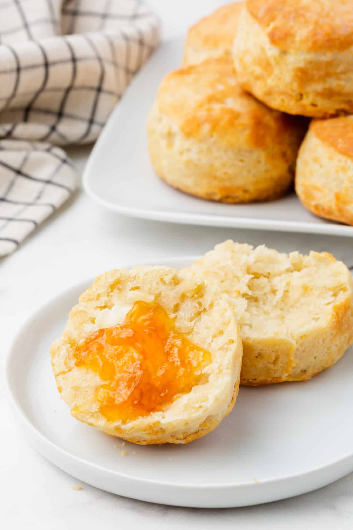 Photo of an air fried frozen biscuit, cut in half with apricot jam spread on half. 