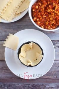 vertical photo showing lasagna pasta lining a jumbo cupcake mold
