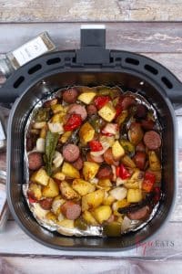 vertical photo showing air fryer sausage meal in the air fryer basket,, cooked