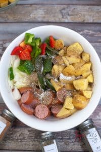 vertical photo showing all ingredients for air fryer sausage meal in a large white bowl
