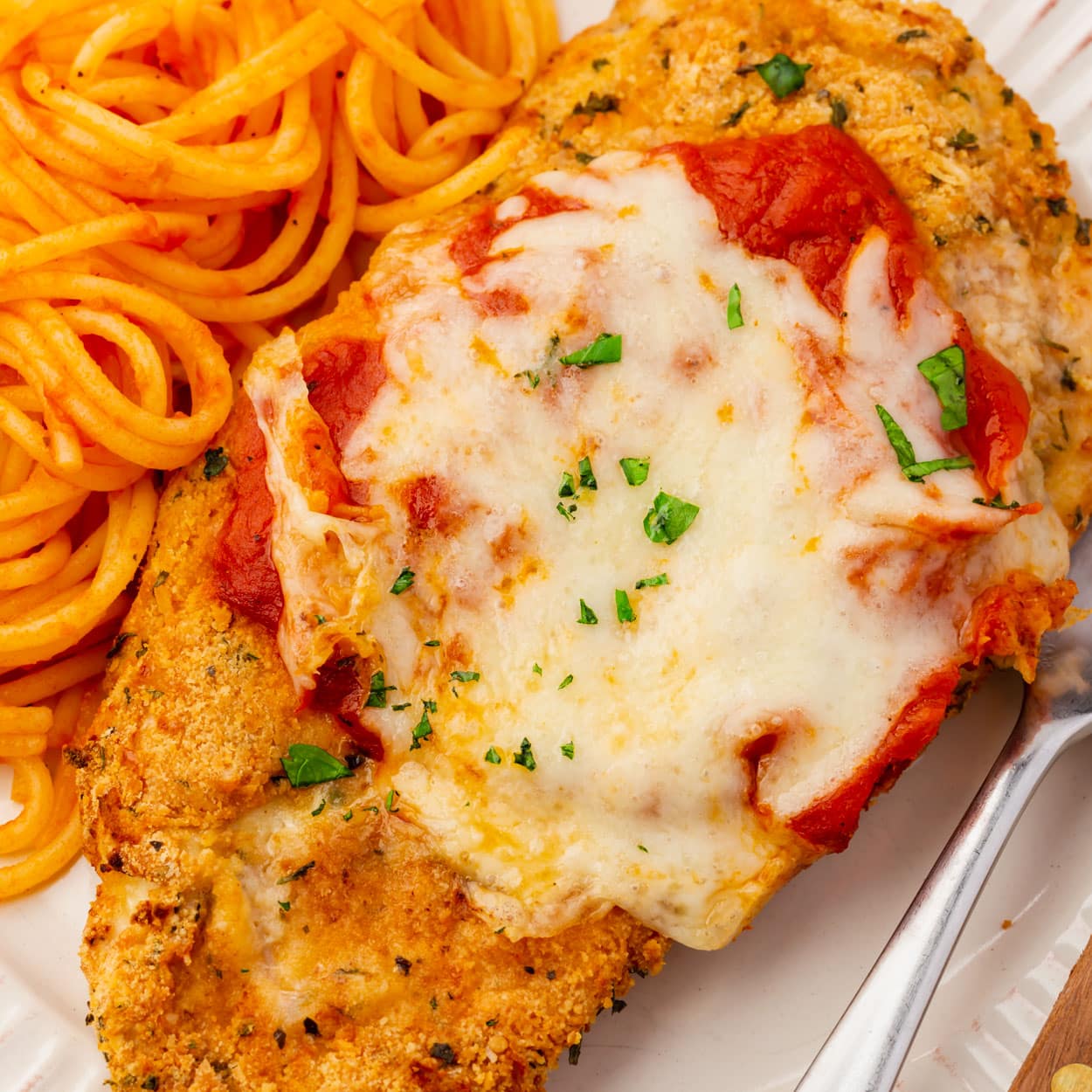 Closeup of a breaded chicken parmesan cutlet topped with tomato sauce and mozzarella cheese.