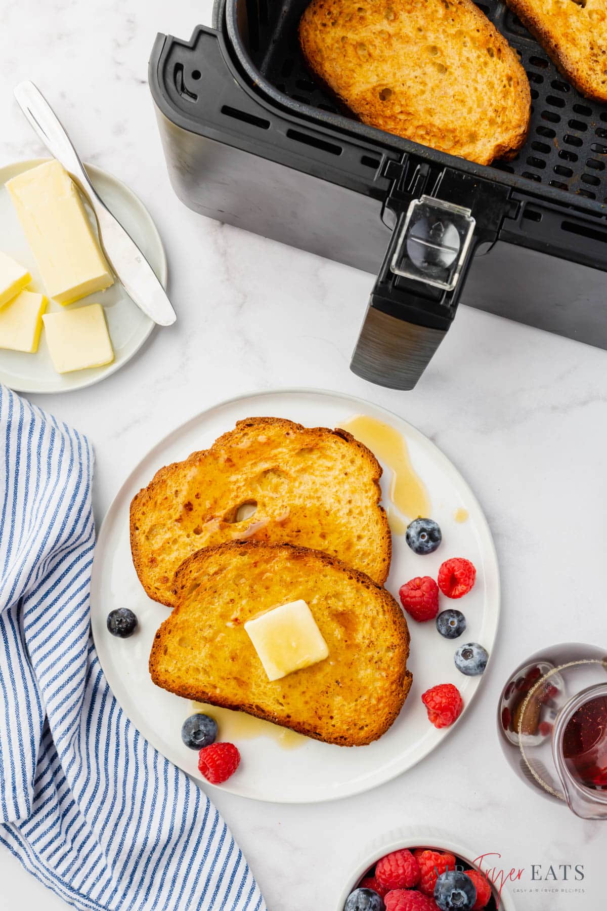 a plate of french toast and berries next to an air fryer basket