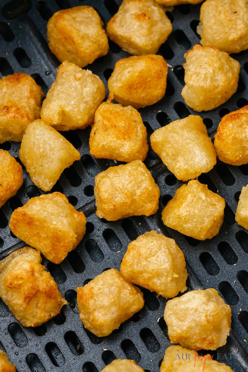 Top view photo of golden brown air fried gnocchi, in the basket of the air fryer. 