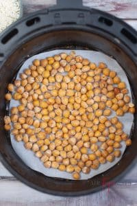 vertical photo showing cooked garbanzo beans in the parchment paper lined air fryer basket