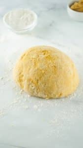 vertical photo showing the dough for air fryer dog treats on floured parchment paper
