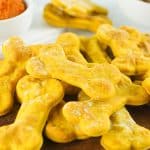 horizontal image showing a pile of air fryer dog treats on a wooden board