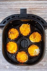 vertical photo of 6 air fryer breakfast bites in an air fryer basket, cooked