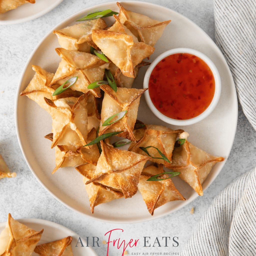 a round plate with crispy air fryer crab rangoons and a side of sweet and sour sauce