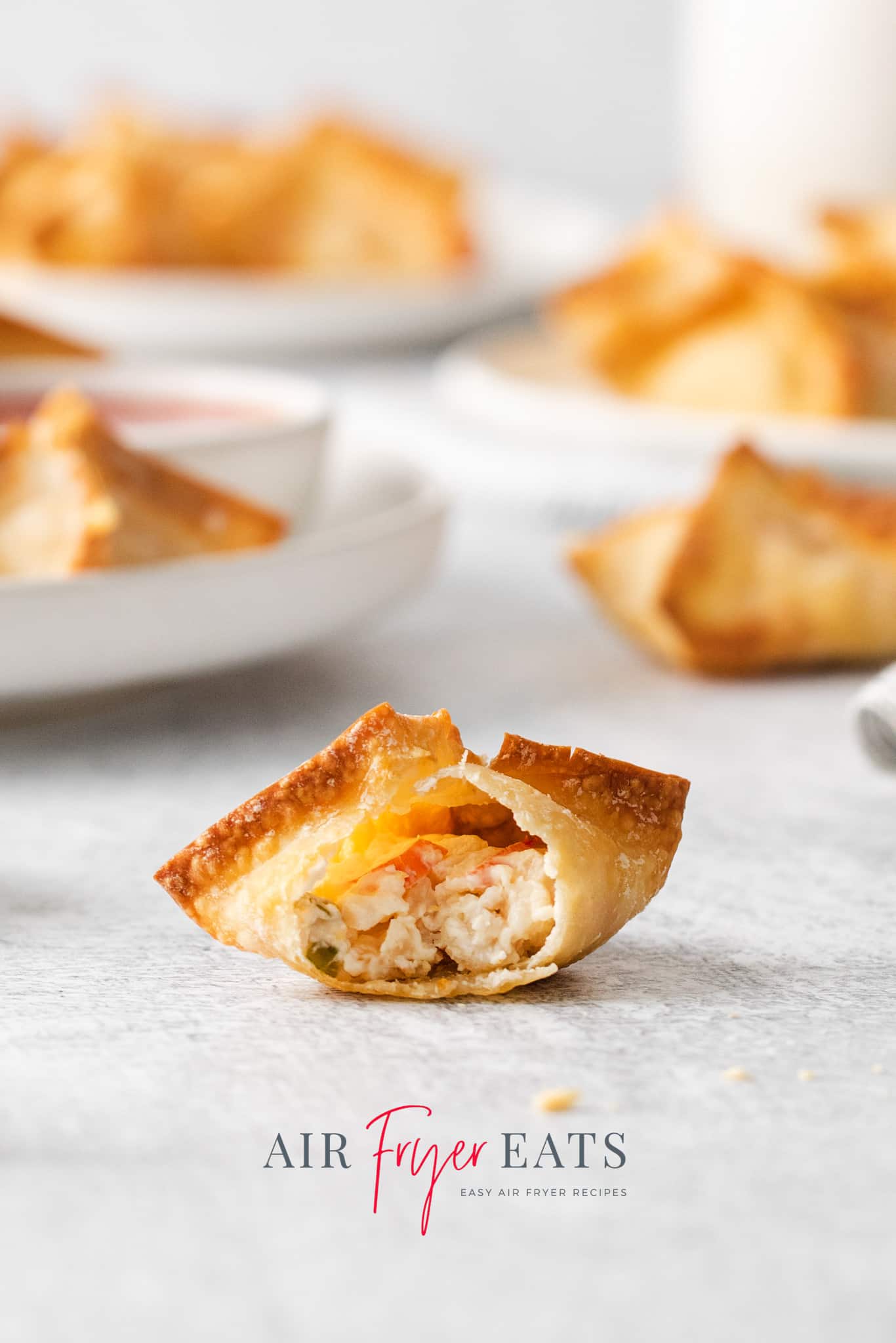 an air fryer crab rangoon with crispy edges with a bite taken to show the creamy filling inside.