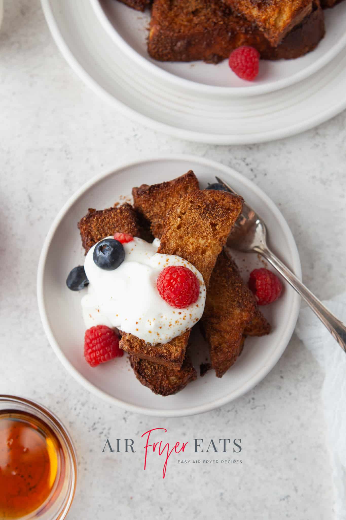 a plate of homemade air fryer french toast sticks topped with yogurt and berries. 
