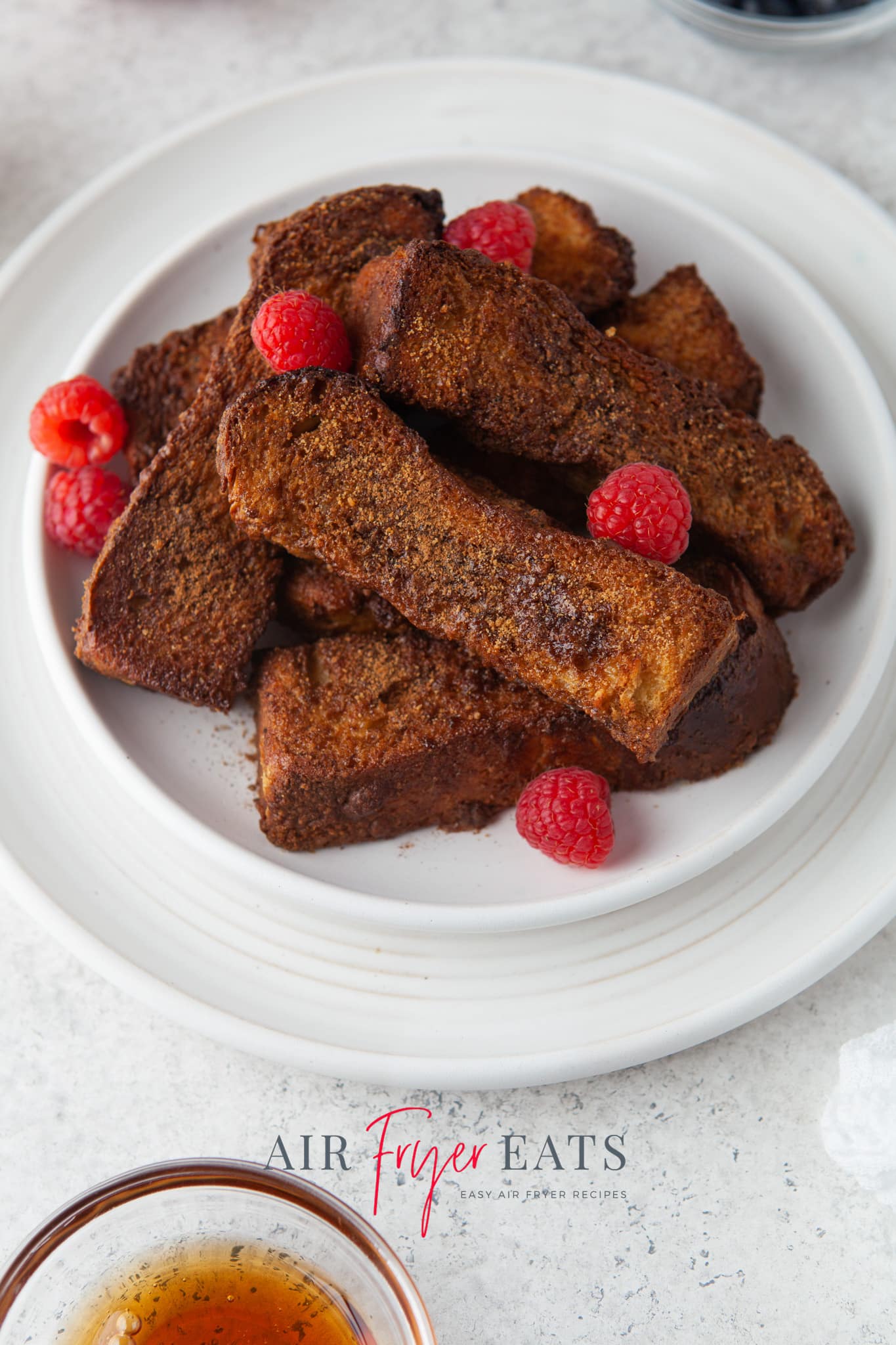 a white plate of cinnamon sugar coated french toast sticks. 