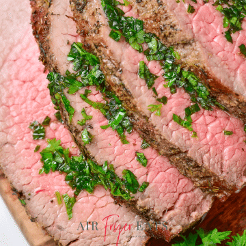 Sliced medium rare steak with fresh herbs.
