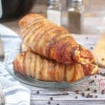 horizontal photo with air fryer bacon wrapped chicken pieces on a glass plate on a wooden surface