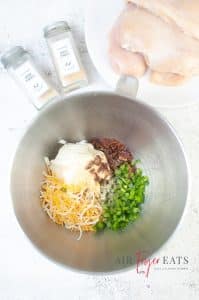 vertical overhead photo of a mixing bowl with cream cheese, shredded cheese, salt, pepper, onion powder, garlic powder, diced jalapenos, and chopped bacon