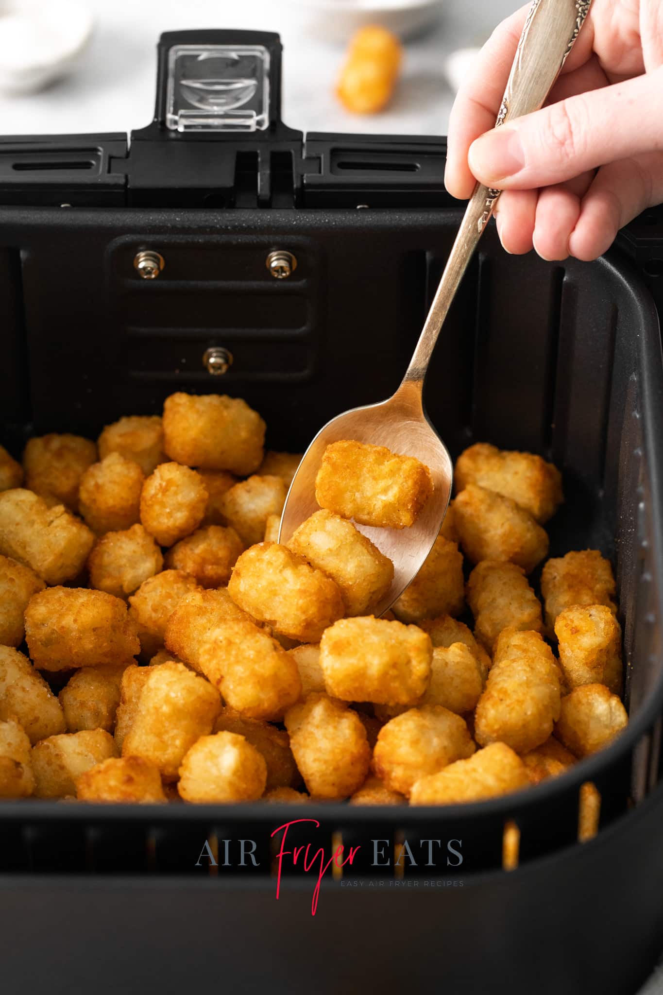 a spoon picking up air fried ore ida tater tots.