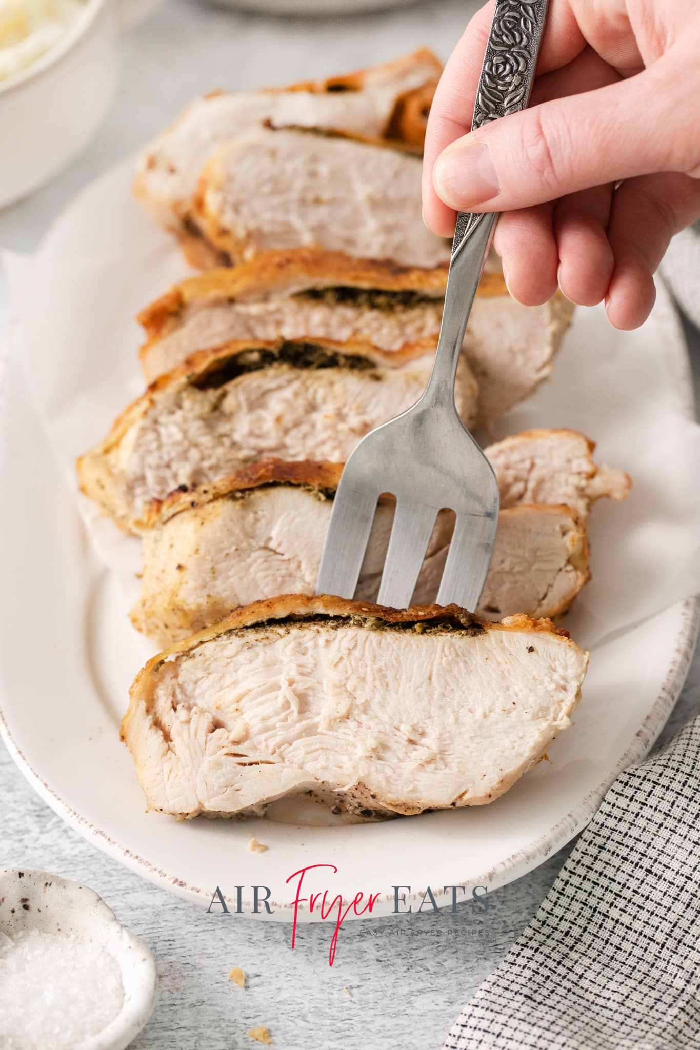 sliced turkey on a platter. A large fork is picking up a serving.