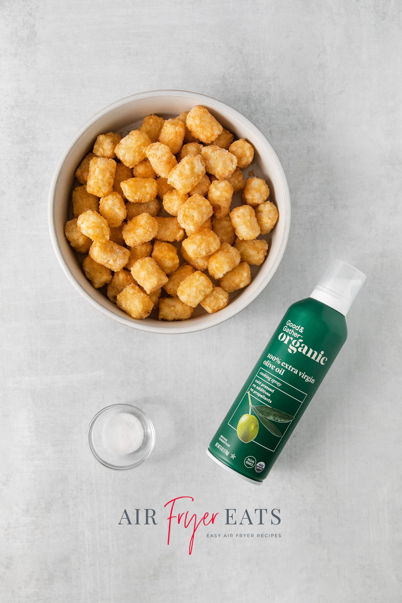 a bowl of frozen tater tots and a bottle of spray oil