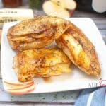 horizontal photo of three air fryer stuffed chicken breasts on a square white plate with some ingredients around the plate