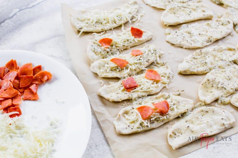 Garlic knot pizza dough filled with mozzarella cheese, pizza sauce, and pepperoni, ready to be rolled into knots and cooked in the air fryer.