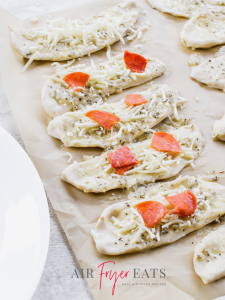 The dough pieces are topped with mozzarella cheese and pepperoni.