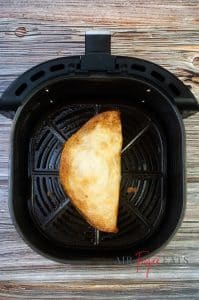 A single cooked air fryer chicken quesadilla is inside an air fryer basket.