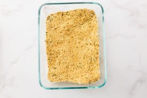 A shallow glass dish contains a breadcrumbs and parmesan cheese mixture.