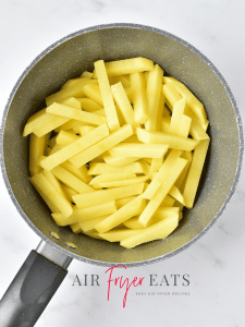 A medium-sized pot is full of cut potato wedges that will be soaked in cold water to remove the starch. Then, they'll be cooked in the air fryer to make garlic parmesan fries.