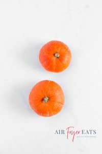 An aerial shot of two small pumpkins on a marble surface.
